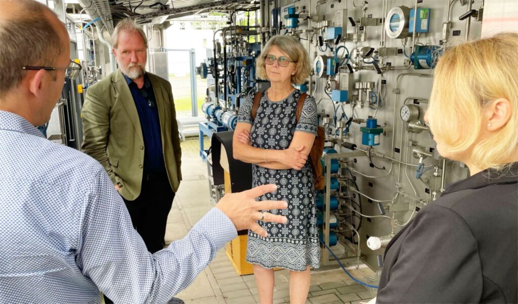 Gesprächsrunde mit Bundestagsabgeordneter Susanne Menge vor der Schalttafel der ZBT-Wasserstoff-Testtankstelle