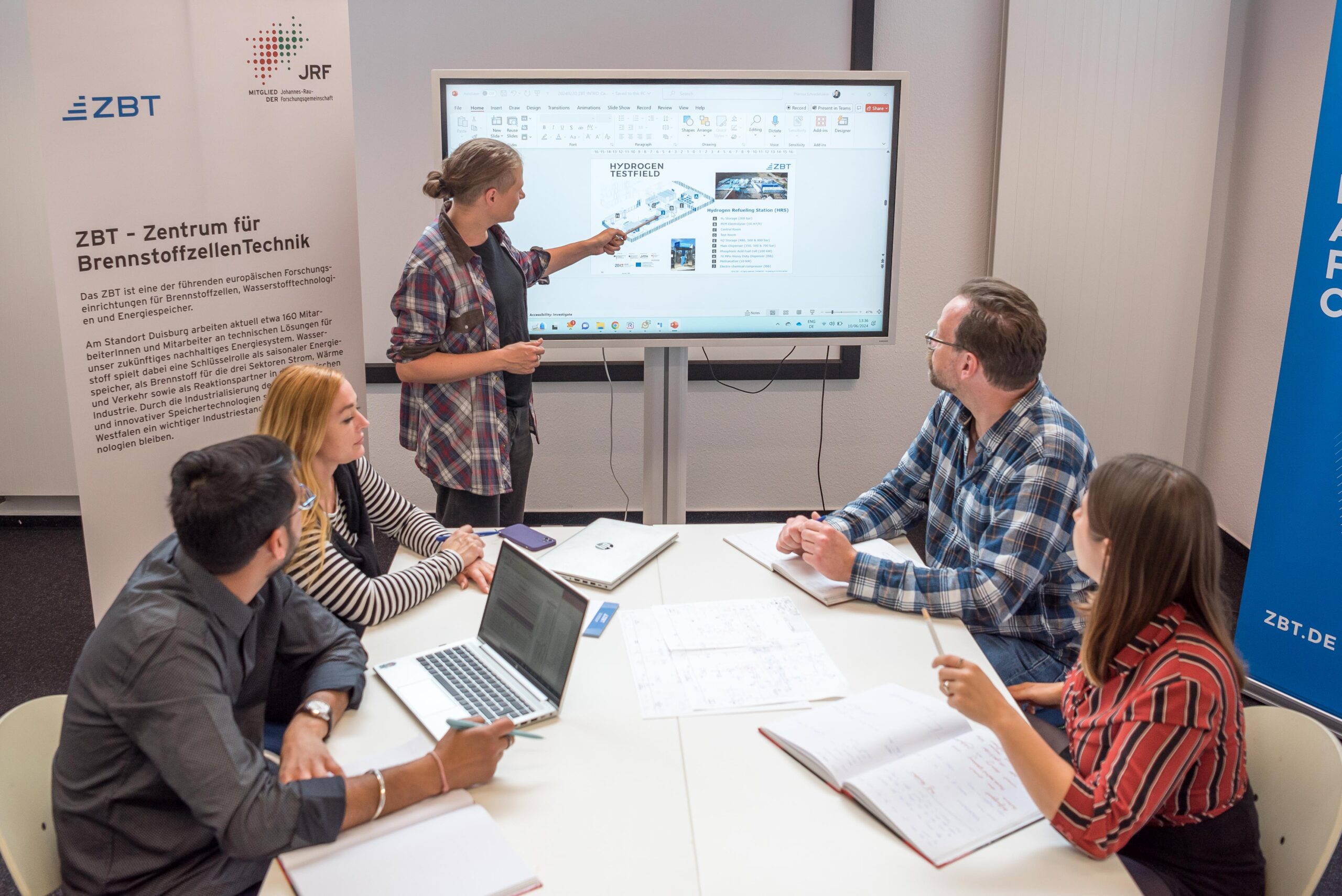 Besprechungssituation mit fünf Personen um einen Tisch