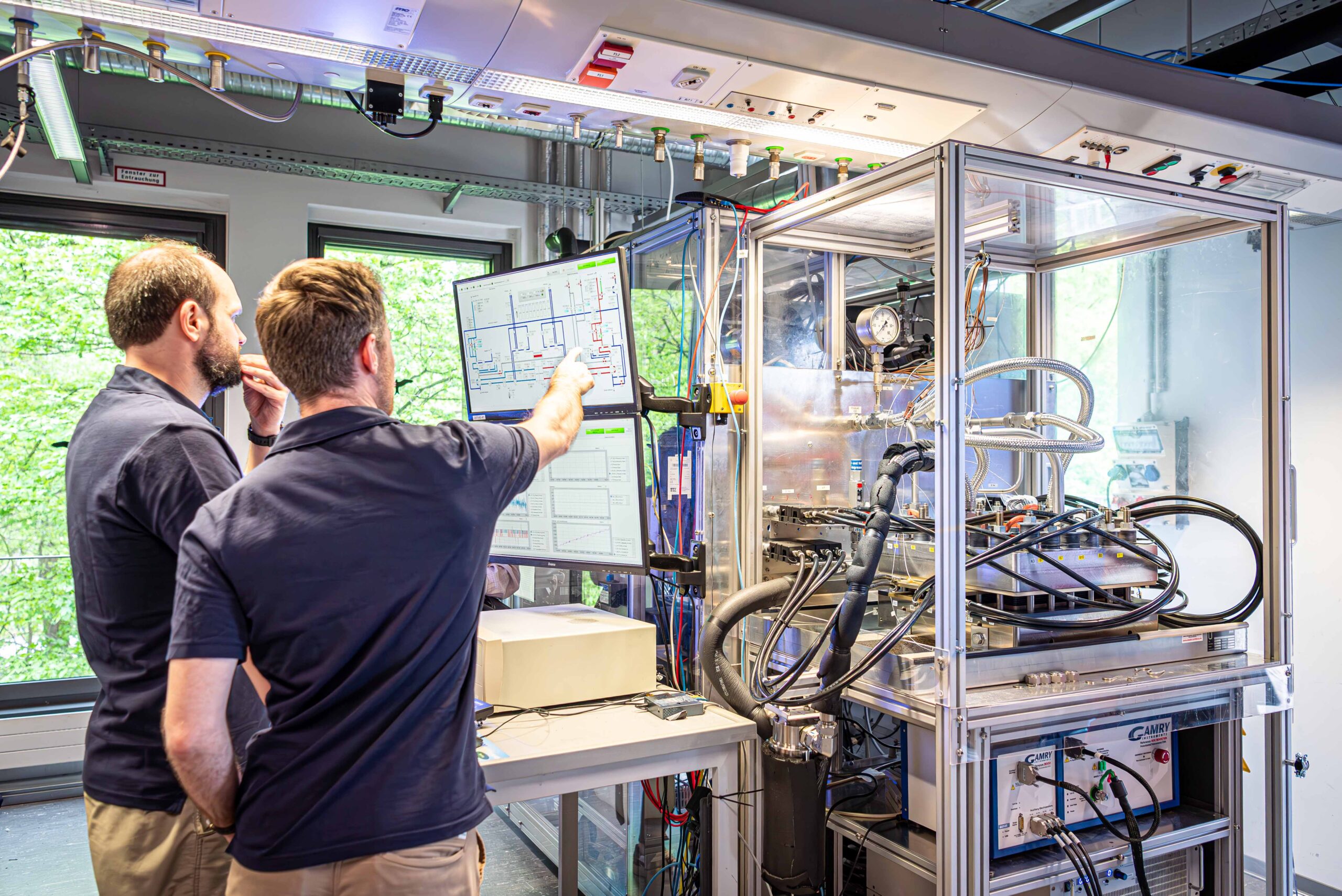 Zwei Personen schauen auf einen Bildschirm, welcher das Bedienelement eines Teststandes ist.
