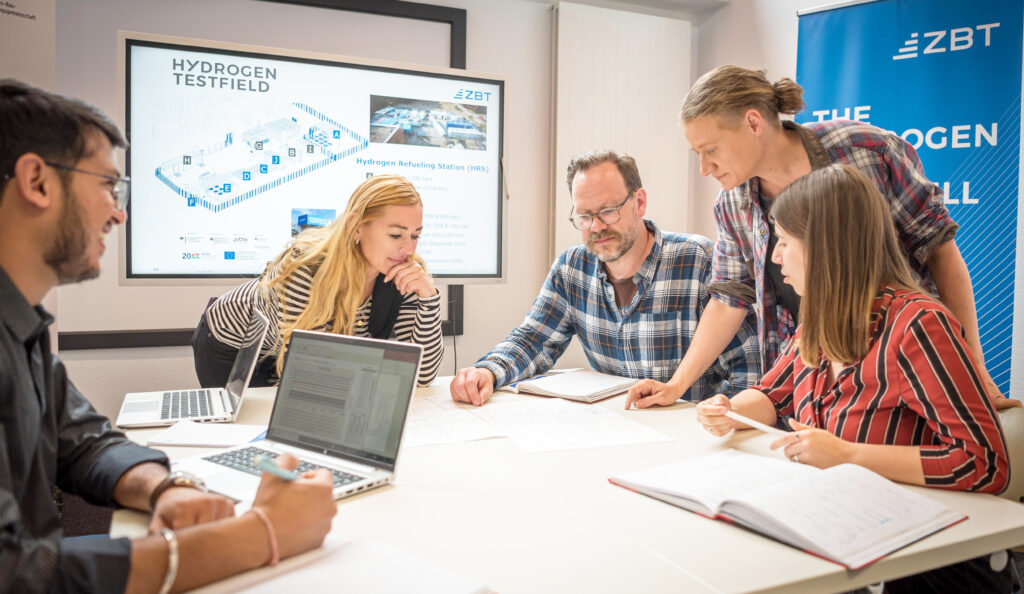 Besprechungssituation mit fünf Personen um einen Besprechungstisch
